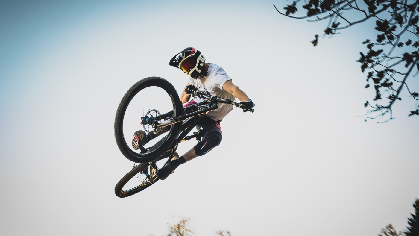 A mountain biker doing tricks on a mountain bike in the air
